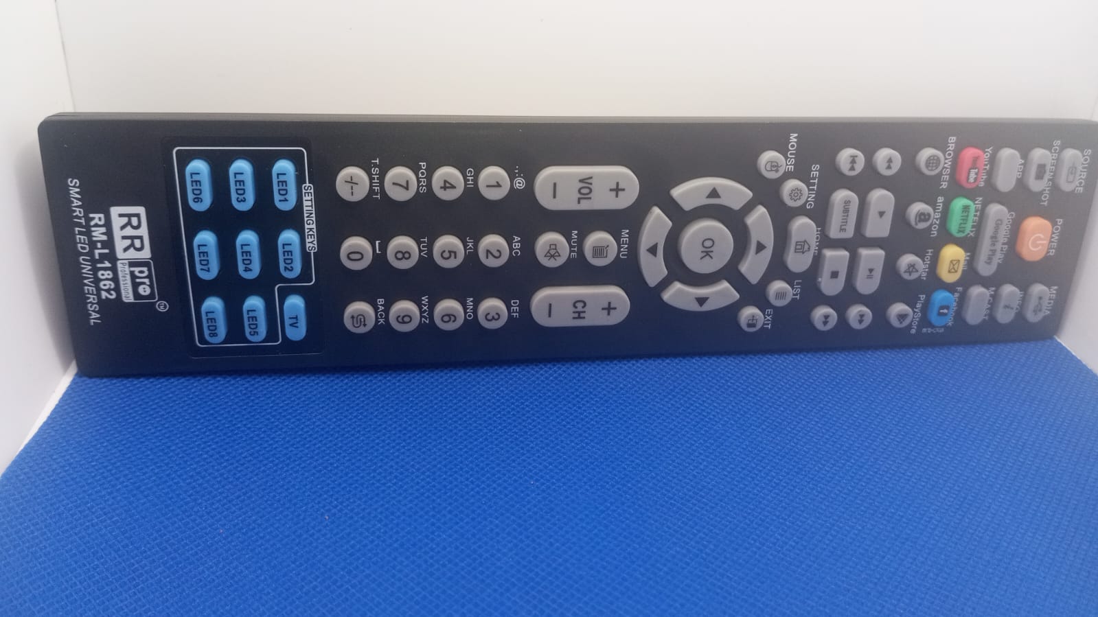 Universal remote control with ergonomic design and various buttons for easy operation on a blue background.